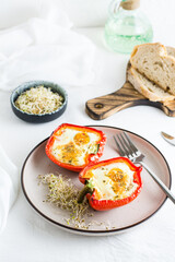 Bell pepper halves baked with egg and microgreens on a plate on the table. Flexitarian organic diet. Vertical view