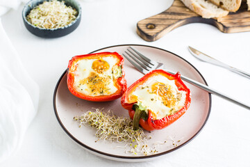 Ready-to-eat bell pepper halves baked with egg and microgreens on a plate on the table. Healthy organic diet