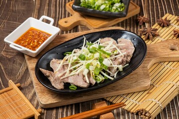 pig mouth meat in a dish with chilli sauce isolated on wooden board side view on table taiwan food