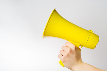 On a white background, a yellow megaphone in a female hand. Symbol of fakes, misinformation. Elections, journalism, yellow press, advertising. There is free space to insert. Banner.