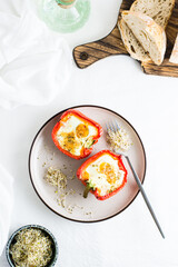 Ready-to-eat bell pepper halves baked with egg and microgreens on a plate on the table. Healthy organic diet. Top and vertical view