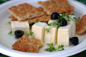 Feta cheese with microgreens, olives and crackers. Healthy snack or snack. White cheese with olive oil.