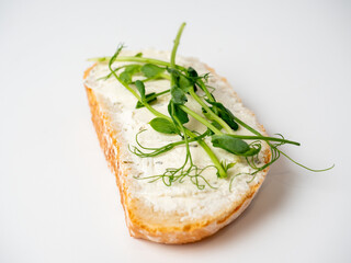 Close-up of a slice of bread spread with cottage cheese and decorated with micro greenery isolated on a white background. The concept of proper nutrition. Healthy snack, diet