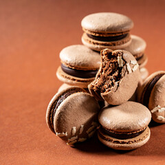 Some sweet tasty brown macarons dessert against a monochromatic brown background.