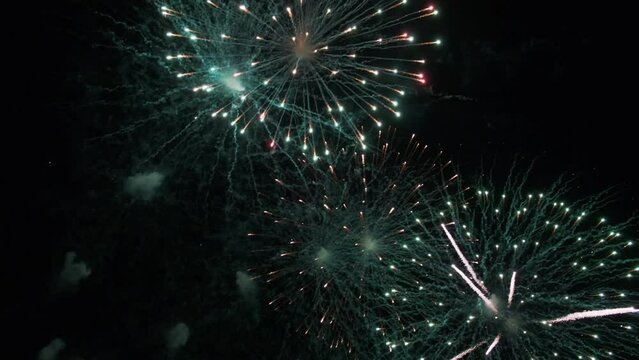 Colorful banger against the dark night sky during a festive event. Glowing fireworks. A real shot of fireworks background. Fireworks with particles and sparks in the black night sky.