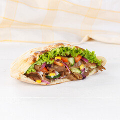 Döner Kebab Doner Kebap slice fast food in flatbread on a wooden board square