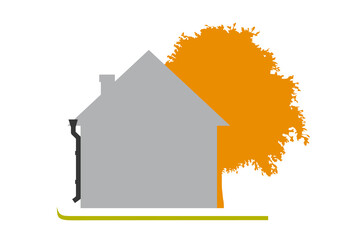 House on a green lawn next to a autumn tree. A flat one-color house, simple in shape. Sunny day