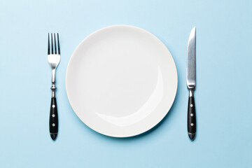 Empty plate and silverware on blue background