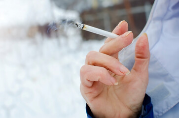 Smoking lit cigarette in hand, close-up. Bad habits, unhealthy lifestyle.