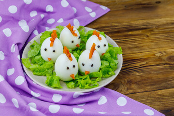 Funny easter breakfast with boiled eggs as chicks on wooden table