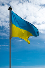 The national flag of Ukraine against the blue sky with clouds