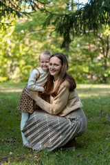 Mom and daughter are hugging in the park. Family walk. Happy mom and daughter. Green Park. Family values. Tenderness and love.