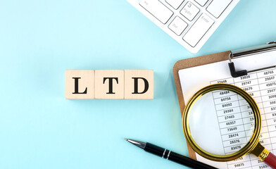 LTD word on wooden cubes on a blue background with chart and keyboard