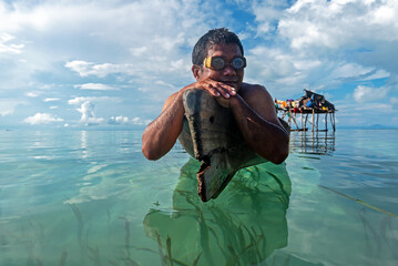 Portrait of Bajau Laut or Sea Gypsy man on a boat with scuba glass in Maiga island Semporna Sabah...