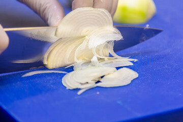 The cook slices the onion into thin slices.