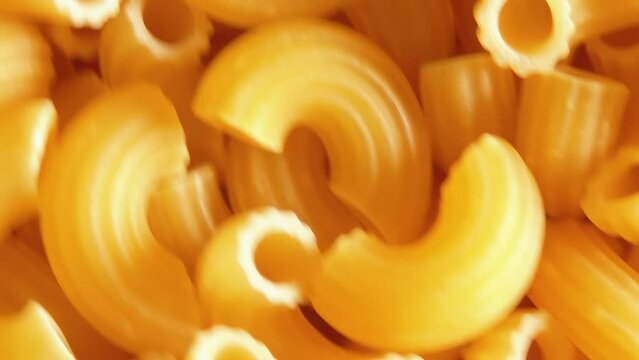 Uncooked Chifferi Rigati Pasta - Top View, Close-Up. Fat and Unhealthy Food. Classic Dry Macaroni, Rotating Background. Italian Culture and Cuisine. Raw Golden Pasta Texture - Left Angular Rotation