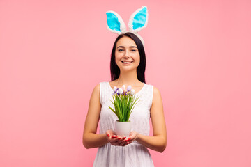 Happy woman in rabbit ears flower with painted eggs, traditional holiday, in the studio on a pink...