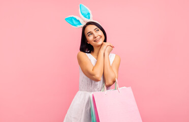 Dreamy woman in rabbit ears with shopping bags in her hands, spring shopping, traditional holiday