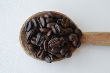 Coffee beans in a wooden spoon isolated on white background