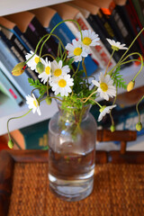 a bouquet of daisies in a vase on the background of books