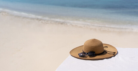 Fototapeta na wymiar Straw hat on a sunbed on a background of white sand and sea of the Maldivian beach