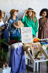 Young women at swap home party - clothes, shoes, bags, jewellery exchange between friends. Zero...