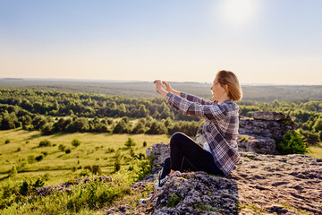 Female hiker photographing landscape with mobile phone during sunny summer hike