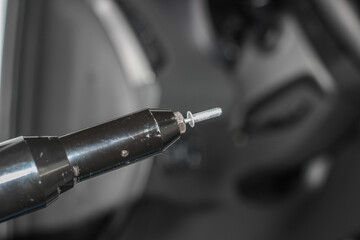 Rivet gun, applicator and rivets. Installing the speaker in the car. An auto mechanic installs a car speaker from the door using a rivet. The process of working with a rivet close-up.