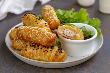 Crab Sticks in Puff Pastry. Baked puff pastry rolls or buns with filling served on a plate with...