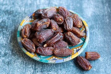 Dried dates on a blue ceramic plate. Close up photo of sweet dates on a table. healthy eating concept. 