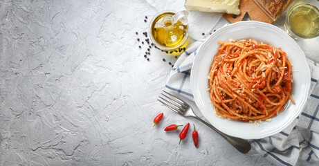 Bucatini amatriciana. Amatriciana pasta, with peeled tomatoes, pecorino cheese, guanciale, extra virgin olive oil, white wine, pepper and chilli, on white plaster background, top view, space for text.