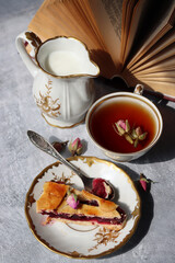 Sweet berries pie, cup of tea, small silver spoon and jug of milk on a table. Beautiful weekend breakfast on a table. 