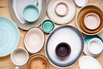 Dishes for serving and eating meals on a wooden background, top view. Modern ceramic and wooden crockery, trendy tableware.