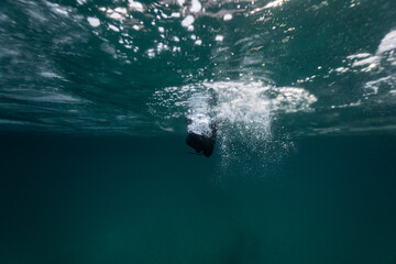 A freediver swimming in between the ice sheets in the icy cold Norwegian waters