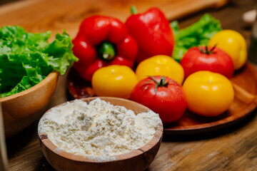 a wooden bowl of flour and vegetables on the kitchen table. farm products