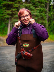 Beautiful redheaded woman prepares for Salmon fishing, on Quartz Creek, in Alaska.  Late Summer.