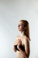Beautiful girl with burnt orange hair posing in studio against gray background...