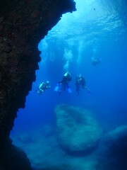 Fototapeta na wymiar scuba divers under the boat coming up sun beam and sun ray on the surface underwater ocean scenery ascending descending