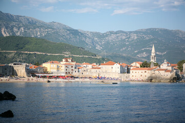 Fototapeta premium View of old town Budva with city beach, Montenegro. The resort city located in Budva Riviera of Adriatic Sea for poster, branding, calendar, card, banner, cover, post. A place for your design or text