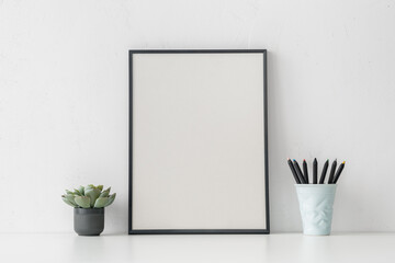 Poster frame and plant on bright beige wall. Stylish home decor design. Mockup..