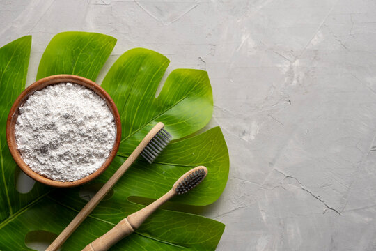 Bamboo toothbrushes and dentifrice or tooth powder made with natural ingredients on gray background
