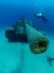 scuba divers exploring and taking photos tank wreck underwater