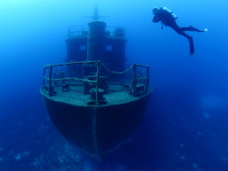 scuba divers exploring and discovering the ship wreck underwater deep sea bottom metal on ocean...