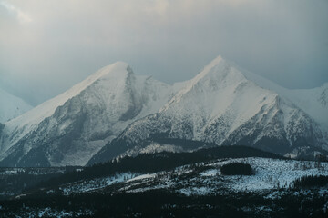 Fototapeta na wymiar Tatry Wysokie o świcie, zima, szczyty w chmurach, Karpaty, widok z przełęczy nad Łapszanką.