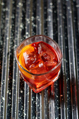 Cocktail Negroni com torção de laranja no fundo escuro e rudtico. Fotografia de bebidas.
