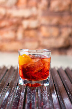 Cocktail Negroni com torção de laranja no fundo escuro e rudtico. Fotografia de bebidas.