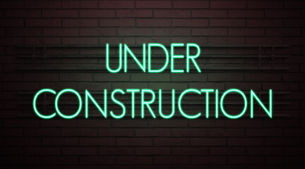 Fototapeta na wymiar neon sign with message UNDER CONSTRUCTION in front of a brick wall