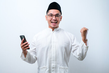 Asian muslim man holding smartphone doing winning gesture holding mobile phone, Happy get special gift online