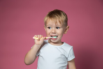 Smiling caucasian little boy cleaning his teeth with manual children toothbrush