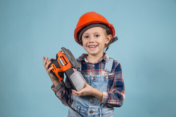 Cute little caucasian kid in orange safety helmet,holding electric sander